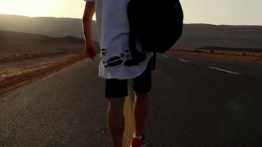Yalnız Yakışıklı Adam Yürüyüşü ve Eğlencesi. Kendine güvenen adam gün doğumunda yolda yürüyor. Adam çölde yürüyor..