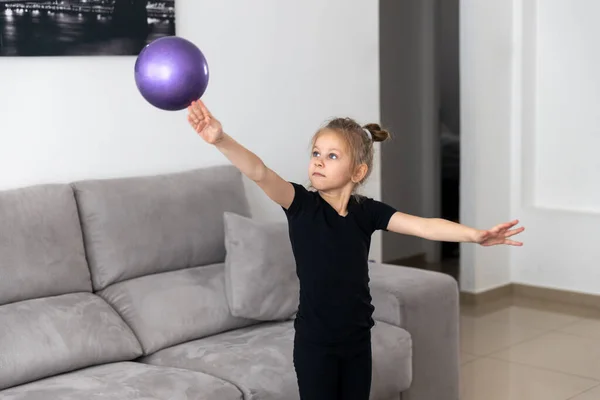 Niña gimnasta, realiza varios ejercicios de gimnasia y fitness. El concepto de infancia y deporte, un estilo de vida saludable — Foto de Stock