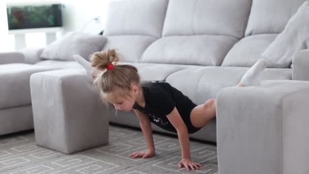 Internetundervisning. liten flicka gymnast gör sport övningar och stannar hemma i karantän — Stockvideo