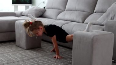 Küçük tatlı kız evde jimnastik yapıyor. Online eğitim. Esniyor, sicim