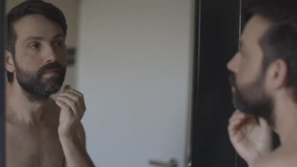 Férfi rövid szakállal megérinti az arcát tükör visszaverődés — Stock videók