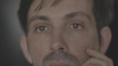 Adam banyoda duruyor. Yüzünü inceler. Yüzünde kısa bir sakal var. Aynadaki yansıma. Hijyenik prosedürler