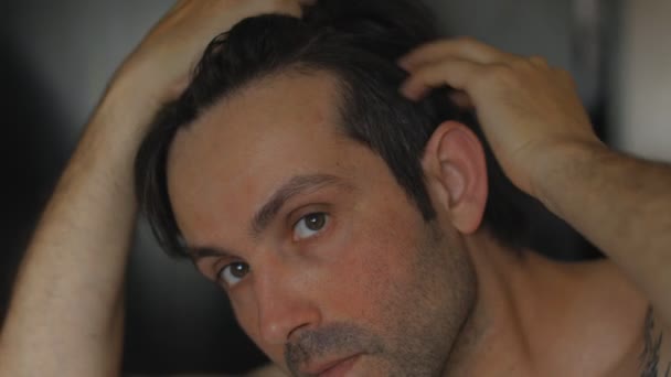 Kaukaski mężczyzna martwi się o wypadanie włosów i patrząc w lustro jego cofające się włosy — Wideo stockowe