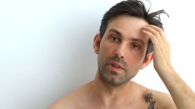 Çekici adam saçının dökülmesinden endişeleniyor. Adam merceğe bakarak saç çizgisini kontrol ediyor. Adam saçının dökülmesinden endişeleniyor.