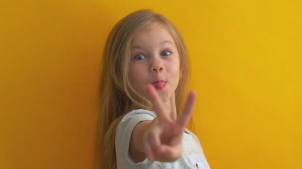Забавна дівчинка на жовтому тлі, що показує номер два, символ підрахунку, концепція математики, впевненість і веселість — стокове відео