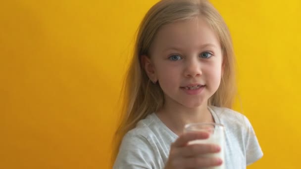 Portrait de belle fille avec verre de lait sur fond jaune — Video