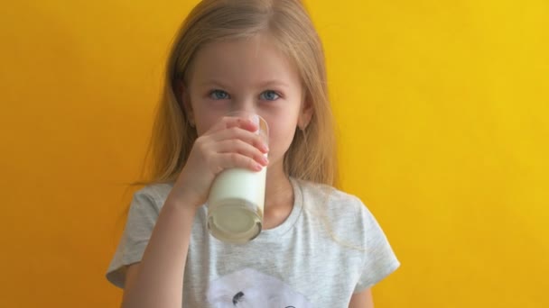 Счастливая девушка держит стакан молока на желтом фоне. Наслаждаясь натуральным коровьим молоком. И питание. Здоровое питание — стоковое видео