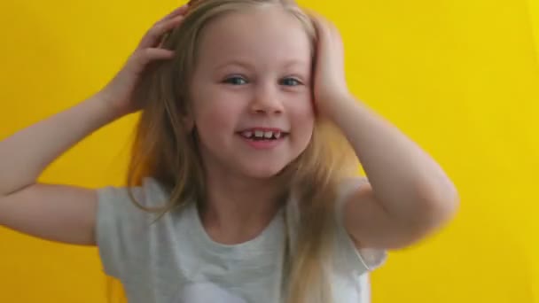 Niña positiva emocionalmente hace caras y juega con su cabello rubio. Retrato de cerca. Feliz, lindo niño pequeño, 6-7 años — Vídeos de Stock