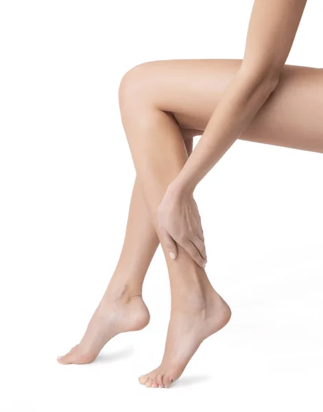 Mujer tocando sus piernas femeninas bellamente arregladas sobre un fondo blanco — Foto de Stock