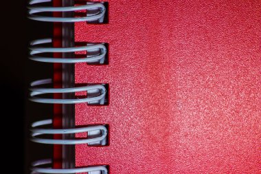 Koyu arkaplanda spiralleri olan kırmızı defter yakın çekim dokusu