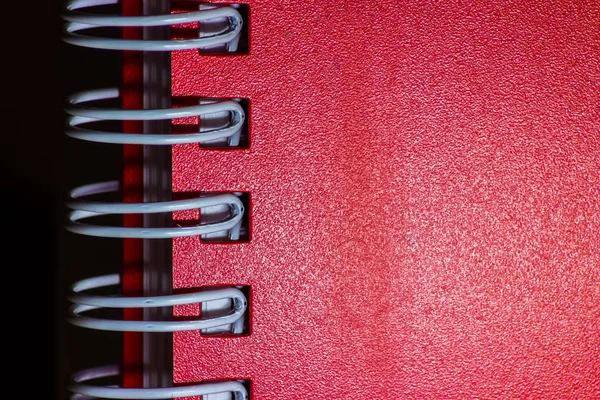 Koyu arkaplanda spiralleri olan kırmızı defter yakın çekim dokusu