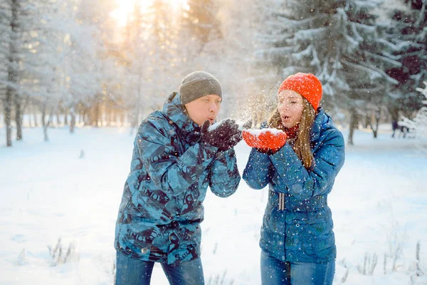 A couple walks in the Park in winter and playing with snow, blows snow from her hands — Stock Photo, Image