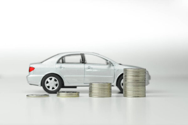 Концепция автомобиля и денег - стопки монет перед седаном

