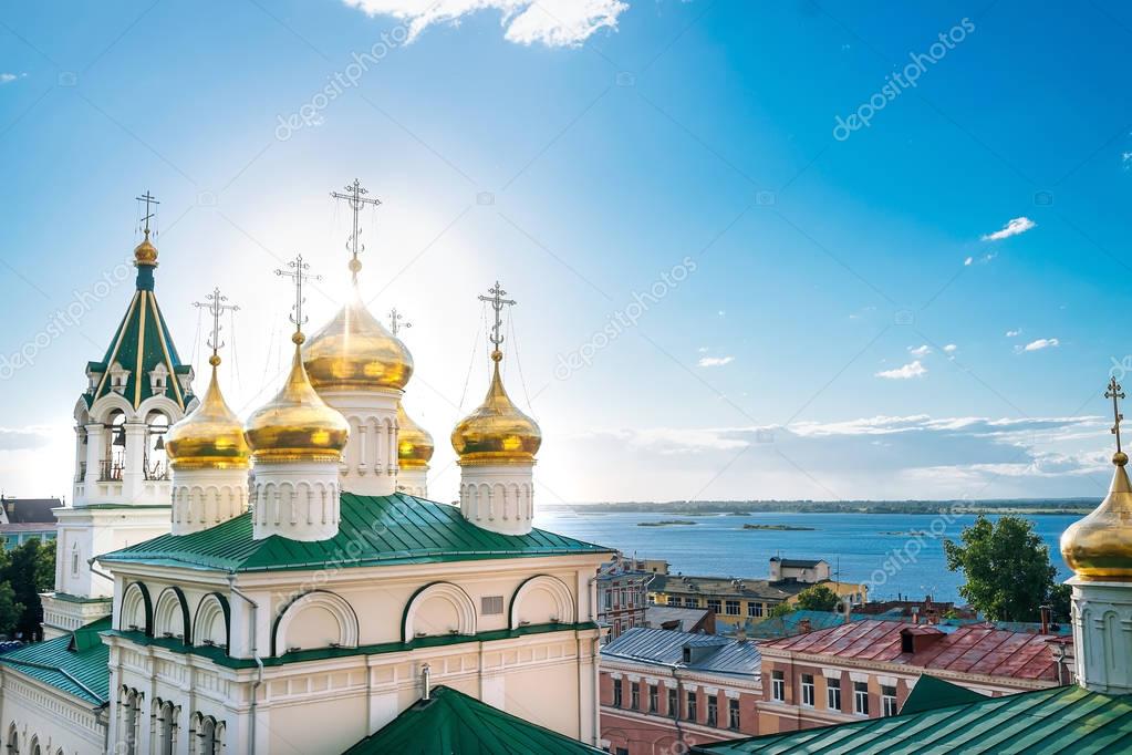 Golden domes with crosses on Orthodox Church of St John the Baptist, on the background of blue sky and Volga river. Russia, Nizhny Novgorod