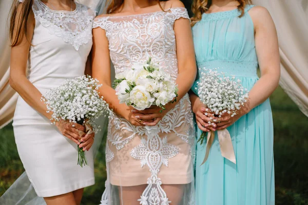 Gelin ve iki nedime ellerinde düğün buketi tutuyorlar.