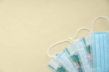 Rus parası, 1000 rublelik banknotlar sarı arka planda koruyucu tıbbi maskelerle karıştırılmış. Koronavirüs salgınındaki ekonomik krizi hesaba katın