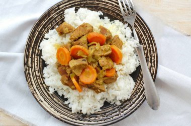 Hindi eti Hint baharat, havuç ve siyah plaka, kumaş ve ahşap çatal ile pirinç ile sağlıklı yemek