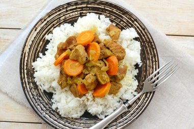 Hindi eti Hint baharat, havuç ve siyah plaka, kumaş ve ahşap çatal ile pirinç ile sağlıklı yemek