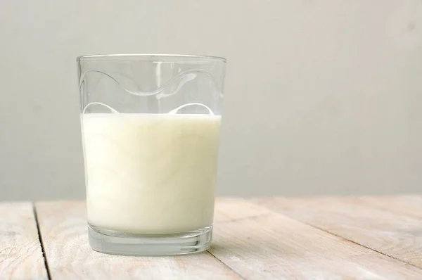 Белое молоко в стекле на деревянном фоне — стоковое фото