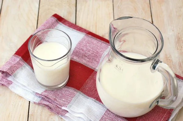 Fehér tejet a pohár a kancsót, a fából készült háttér — Stock Fotó
