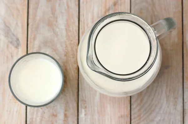 Weiße Milch im Glas mit dem Krug auf dem Holzgrund — Stockfoto