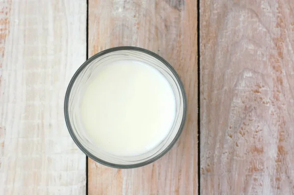 Λευκό γάλα στο ποτήρι με το ξύλινο υπόβαθρο — Φωτογραφία Αρχείου