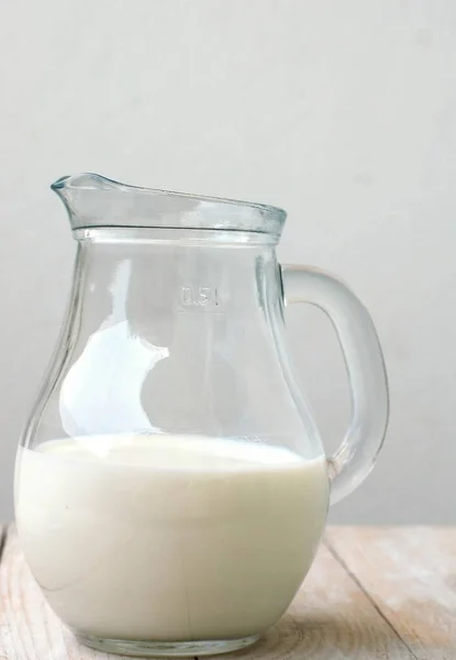 Bílé mléko v konvici na dřevěné pozadí — Stock fotografie