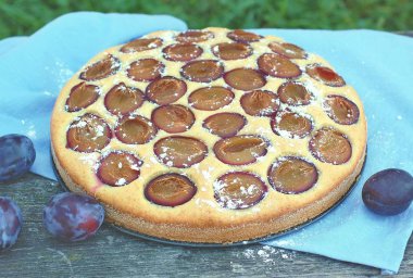 Parça ahşap zemin üzerine mavi kumaş üzerine Erik ile yaz pastası