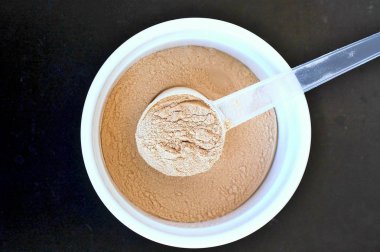 Protein tozu pirinç üzerinden bir bezelye siyah arka plan üzerine plastik kaşık ile beyaz kase bitki