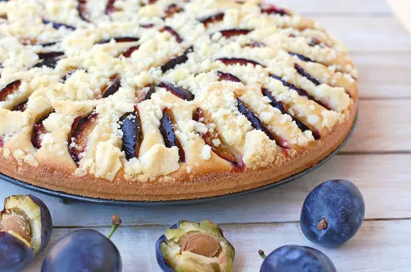 Pedazo de pastel de verano con ciruelas sobre tela azul sobre fondo de madera — Foto de Stock