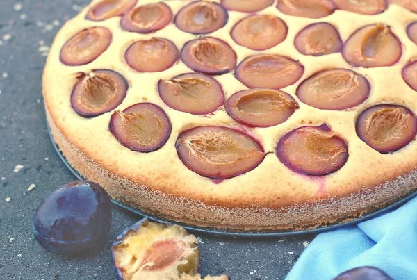 Pedazo de pastel de verano con ciruelas sobre tela azul sobre fondo de madera — Foto de Stock