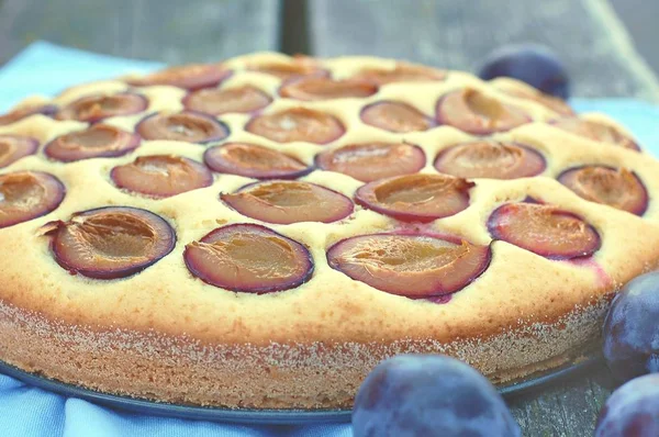 Pedazo de pastel de verano con ciruelas sobre tela azul sobre fondo de madera — Foto de Stock