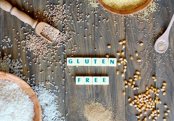Gluten free cereals corn, rice, buckwheat, quinoa, millet and amaranth with text gluten free on grey wooden background