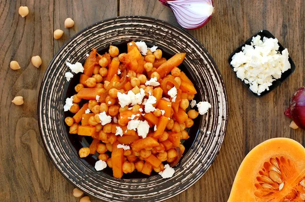 Gesunde Mahlzeit aus Kichererbsen, Kürbis, roten Zwiebeln und Käse auf weißem Teller auf dunklem Holzgrund — Stockfoto