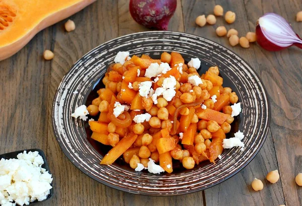 Gesunde Mahlzeit aus Kichererbsen, Kürbis, roten Zwiebeln und Käse auf weißem Teller auf dunklem Holzgrund — Stockfoto