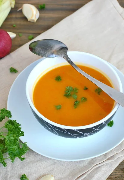 Kabak hokaido, yeşil kereviz, sarımsak, soğan ve maydanoz boxl kaşık kahverengi kumaş ve ahşap arka plan ile sağlıklı turuncu çorbası