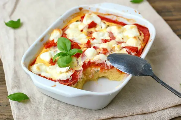 Comida sin gluten de harina de maíz tostada, tomate, queso de cabra y albahaca en un tazón blanco sobre tela sobre fondo de madera marrón —  Fotos de Stock