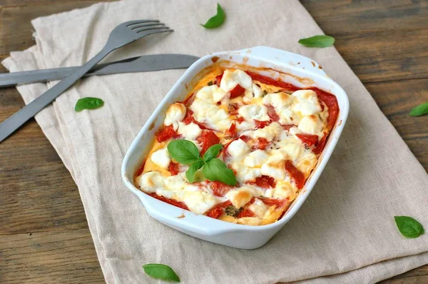 Comida sin gluten de harina de maíz tostada, tomate, queso de cabra y albahaca en un tazón blanco sobre tela sobre fondo de madera marrón —  Fotos de Stock