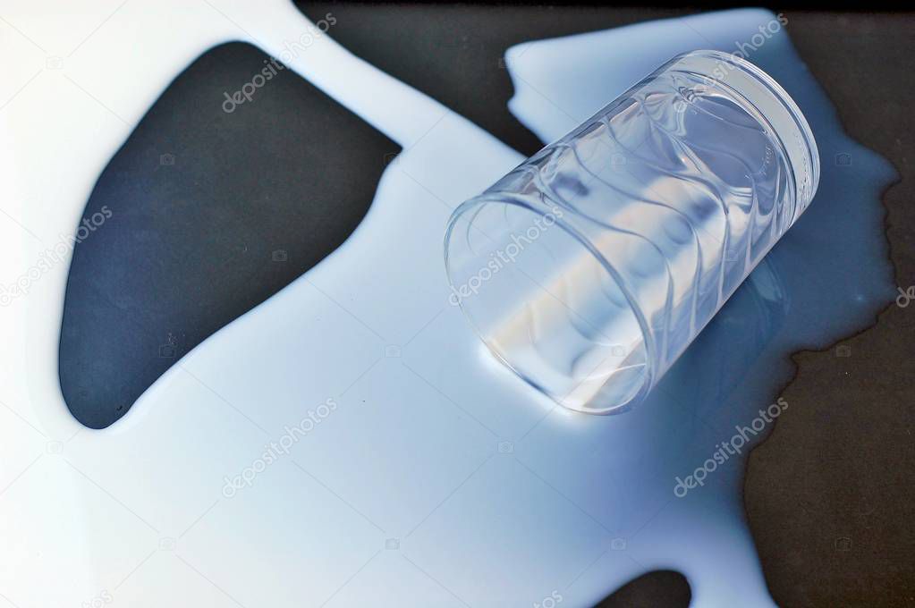 White spilled milk with the glass on the black background