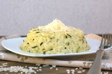Salatalık ve peynir beyaz tabakta çatalı ile kremsi risotto
