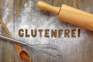 Metin gluten ücretsiz Almanca tahta kaşık, çırpıcı ve koyu kahverengi ahşap arka plan üzerinde oklava ile gluten ücretsiz un