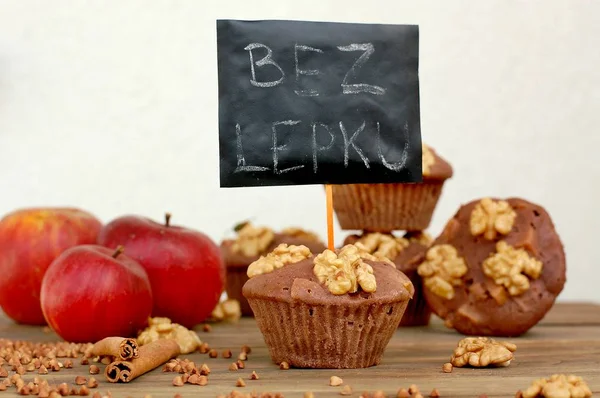 Gluten free muffins from buckwheat flour, apple, cinnamonand walnuts on brown wooden background with index card with text no gluten in czech language