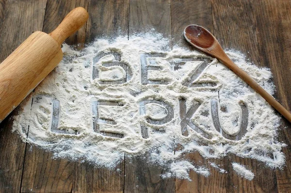 Gluten free flour with text gluten free in Czech language with wooden spoon and rolling pin on dark brown wooden background