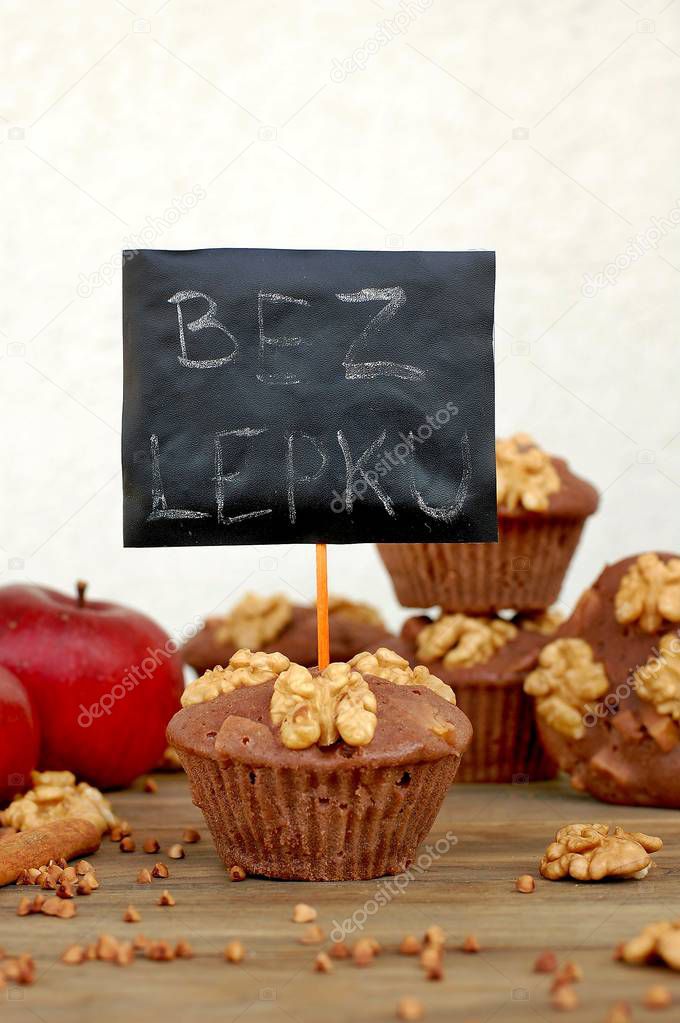 Gluten free muffins from buckwheat flour, apple, cinnamonand walnuts on brown wooden background with index card with text no gluten in czech language