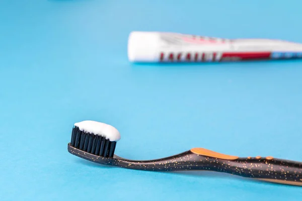Toothpaste on a toothbrush close-up on a blue light background — Stock Photo, Image