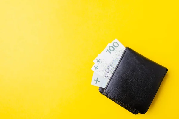 Cartera de cuero negro para hombre con dinero en efectivo sobre fondo amarillo. Desde arriba Fotos de stock