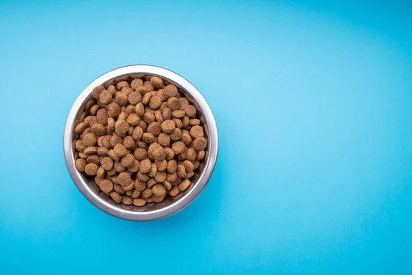 Comida de cão em uma tigela de metal. Fundo azul Fotos De Bancos De Imagens