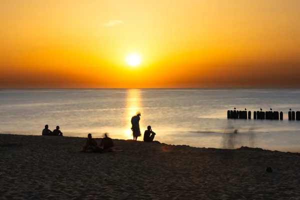 Pessoas na praia durante um belo pôr do sol — Fotografia de Stock