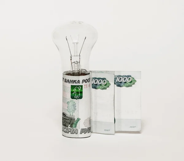 Elektrik lambası ampul ve banknot gri bir arka plan üzerinde dik duran