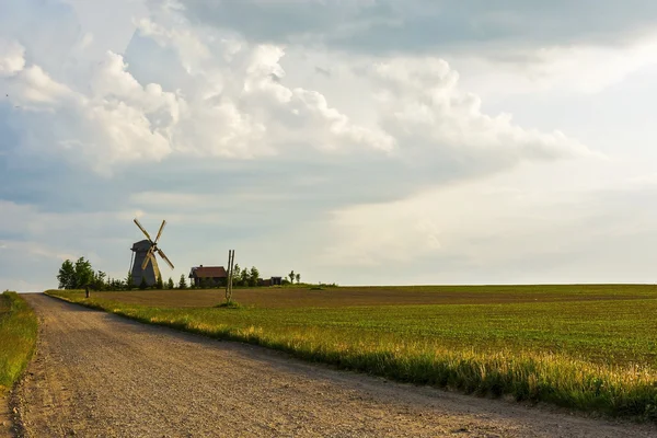 Chemin de terre vers le moulin à vent solitaire et la ferme située parmi les — Photo